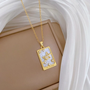 Close-up of gold tarot pendant with mother-of-pearl and THE WORLD engraved lettering