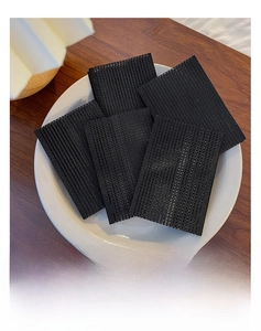 Close-up of five black nylon hair grip pads on a ceramic plate for fixing loose hair