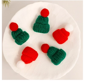 Detailed knit texture of mini Christmas hats in red and green on a white tray
