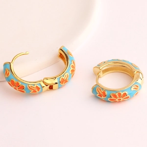 Detail of blue enamel flower earrings with orange patterns and golden C-shape hoops