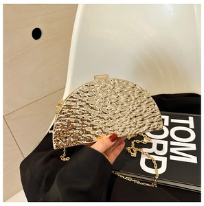 Detail of a golden semicircular evening clutch bag with metallic hammered texture and chain