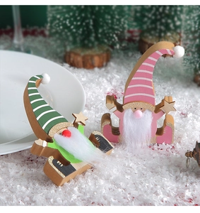 Detail of green and pink wooden Christmas gnomes with striped hats on snowy background