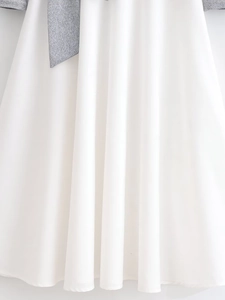 Close-up of elegant pleated white dress featuring a grey bow tie waist detail