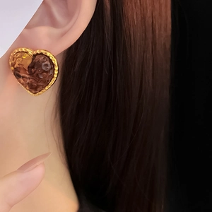 Detail of vintage heart earrings with hammered gold frames and amber resin centers