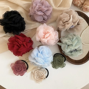 Nahaufnahme eleganter Stoffblumen-Haargummis in verschiedenen Farben mit Blütenblättern