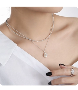 Detail of layered silver necklace with pearl shell pendant and matching silver ring
