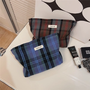 Close-up of vintage plaid cotton cosmetic bag with zipper and woven label on a desk