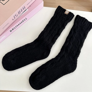 Detailed cable knit texture of black wool socks with small leather label detail