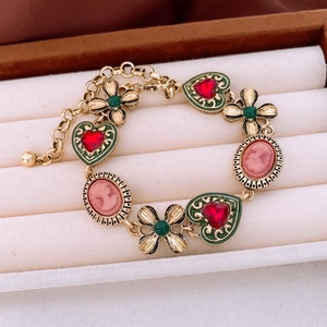 Vintage gold bracelet featuring red heart, green clover, and pink cameo charms in a box