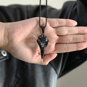 Detail of a vintage black stainless steel raven skull pendant on a metal box chain
