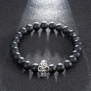 Men's matte black beaded skull bracelet in stainless steel on black textured background