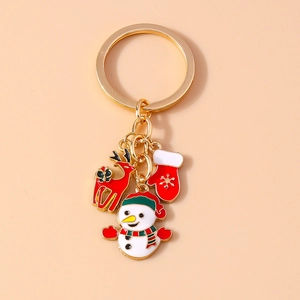 Detail of Christmas keychain with snowman, reindeer and glove charms on pink background