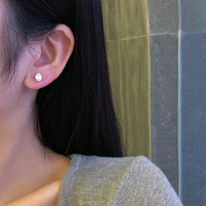 Close-up of S925 sterling silver stud earring with white zircon on a model's ear