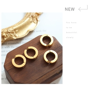 Macro shot of four gold-plated hoop clip-on earrings on a vintage wooden block