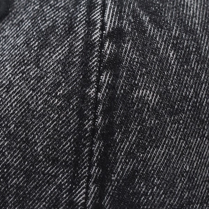 Macro shot of washed vintage black denim texture and reinforced stitching detail