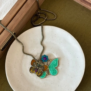 Detail of vintage twin butterfly pendant with green enamel and sparkling blue rhinestone