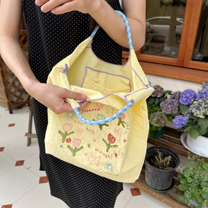 Detail der gelben Canvas-Tasche mit Tulpenstickerei, Karogriffen und Innentasche