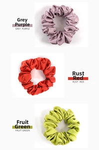 Detailed view of three premium silk scrunchies in grey purple, rust red, and fruit green colors