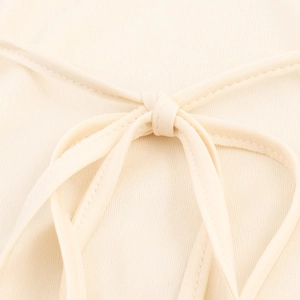 Elegant beige sleeveless dress featuring intricate knot tie details and sequin fabric texture