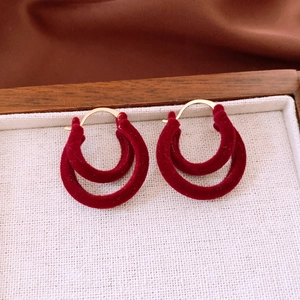 Close-up of wine red flocked double circle earrings with elegant gold metallic finish