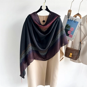 Dettaglio di sciarpa in raso di seta con motivi geometrici su un cappotto beige