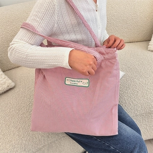 Detail shot of the red gingham fabric texture and Cheerful embroidered patch on tote bag
