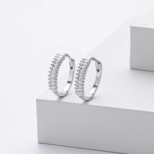 Macro detail of silver hoop earrings with square cubic zirconia on a white block