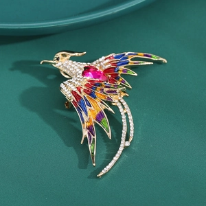 Detailed close-up of golden phoenix brooch with colorful enamel and red gemstone