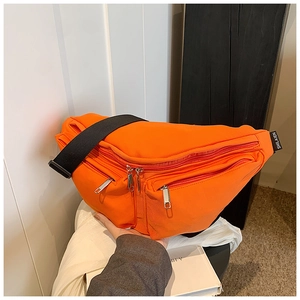 Detail of the bright orange nylon chest bag featuring black adjustable strap and metal zippers
