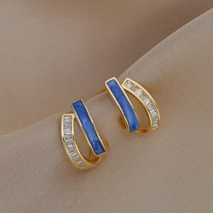 Detail of gold U-shaped earrings with blue enamel and baguette-cut cubic zirconia