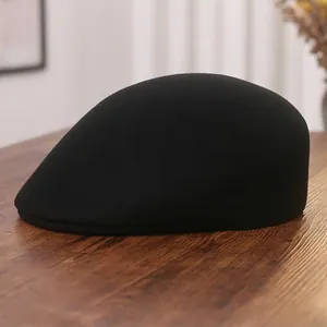 Classic black wool baker boy hat for women on a dark wooden surface, minimalist retro style