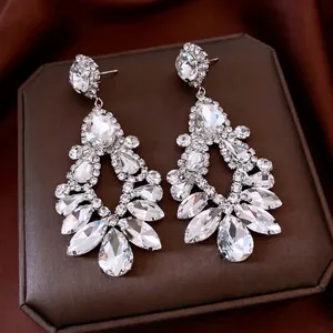 Boucles d'oreilles pendantes en argent avec cristaux en goutte sur fond de soie de luxe