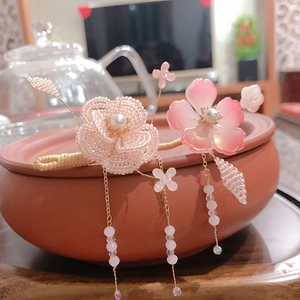 Close-up of a pink beaded floral hair pin with elegant pearl accents and hanging tassels