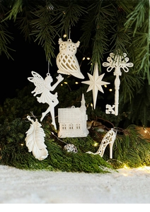 Close-up of white glitter Christmas ornaments including owls and stars on tree branches