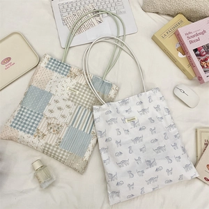 Detailed close-up of patchwork and cat print canvas tote bags on a cozy white cotton bed