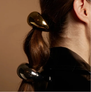 Detailed shot of metallic water drop hair tie on ponytail in gold and gunmetal gray finish