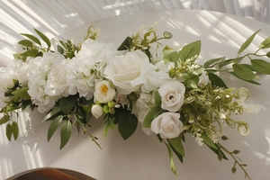 Detail of white artificial rose and hydrangea floral row with realistic green leaves