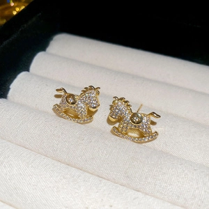 Close-up of golden rocking horse earrings with pavé zircons in a velvet box