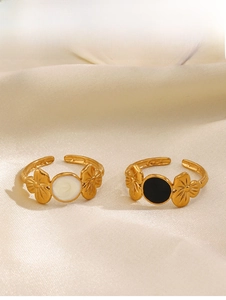 Detail of gold floral open rings with black and white enamel inlays on silk fabric
