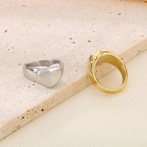 Gros plan de bagues polies en or 18 carats et argent sur pierre montrant un cœur et des textures