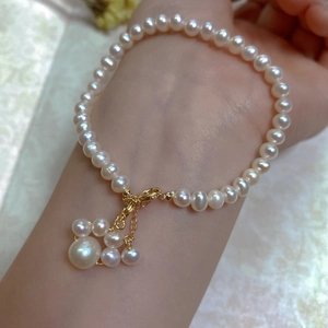 Close-up of baroque pearl bracelet on wrist featuring a cluster pendant and 14K gold clasp