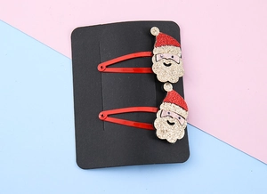 Dettaglio di fermagli per capelli natalizi con Babbo Natale glitterato su carta