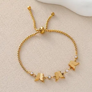 Elegant gold butterfly bolo bracelet with matte charms and zircon accents on a beige surface