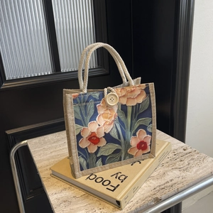 Close-up of linen tote bag with navy floral print and white cotton rope handle on books