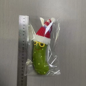 Christmas green pickle plush charm with Santa hat and glasses measured by a ruler