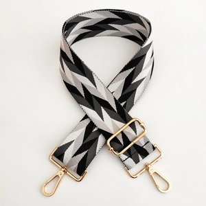 Adjustable woven shoulder strap with black and white V-pattern and gold buckles