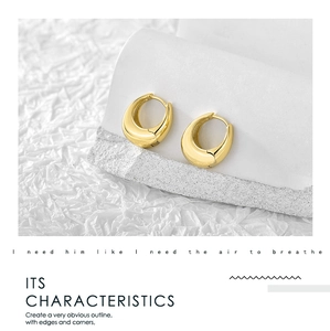 Macro shot of chunky gold plated hoop earrings on a minimalist stone display stand