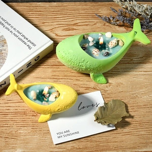 Whale-shaped scented candles in green and yellow with seashells for ocean decor