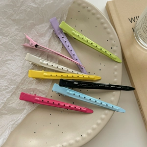 Colorful duckbill hair clips in eight candy shades arranged on a round beige plate