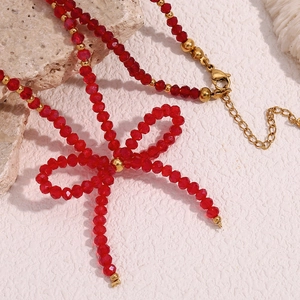 Macro shot of red faceted beads and golden bow pendant with metal lobster clasp